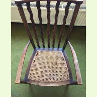 Arts and craft beech wood nursing chair with original cane seat and curved splats.